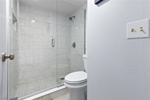 bathroom with toilet and a shower with shower door