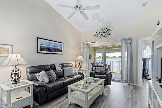 living room with light hardwood / wood-style flooring, high vaulted ceiling, ceiling fan, and a water view