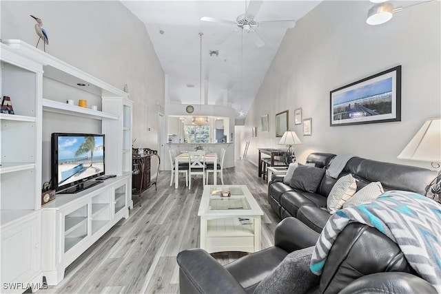 living room with ceiling fan, high vaulted ceiling, and light wood-type flooring