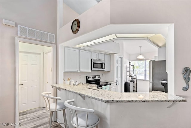 kitchen featuring light stone countertops, white cabinetry, appliances with stainless steel finishes, and kitchen peninsula