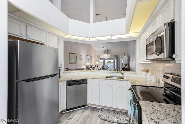 kitchen with white cabinetry, stainless steel appliances, sink, and light stone counters