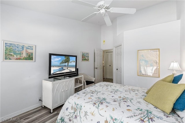 bedroom featuring hardwood / wood-style flooring, ceiling fan, and a towering ceiling