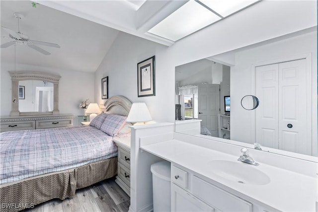 bedroom featuring light hardwood / wood-style flooring, sink, vaulted ceiling, and a closet