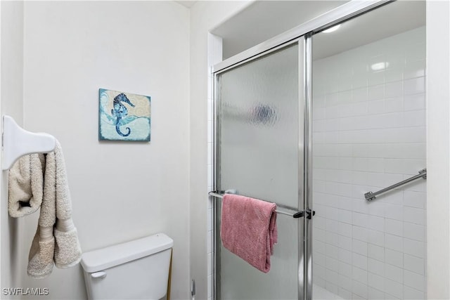 bathroom featuring toilet and a shower with shower door