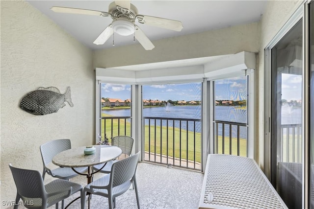 sunroom / solarium with a wealth of natural light, ceiling fan, and a water view