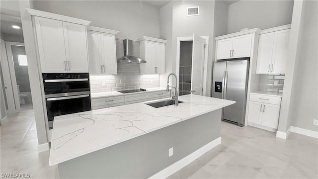 kitchen featuring white cabinetry, wall chimney range hood, stainless steel fridge, and sink