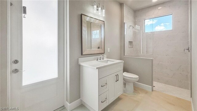 bathroom with vanity, a tile shower, and toilet