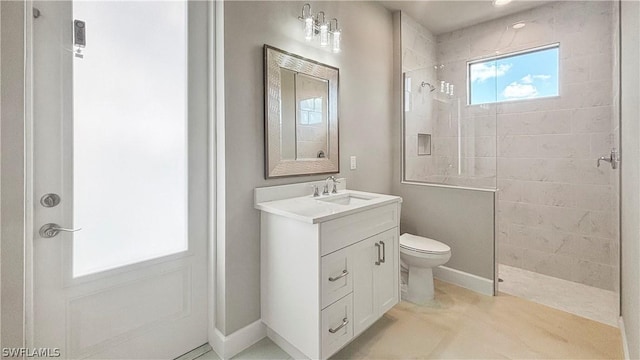 bathroom featuring a tile shower, vanity, and toilet