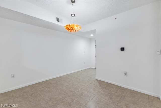 empty room with a textured ceiling and light tile patterned floors