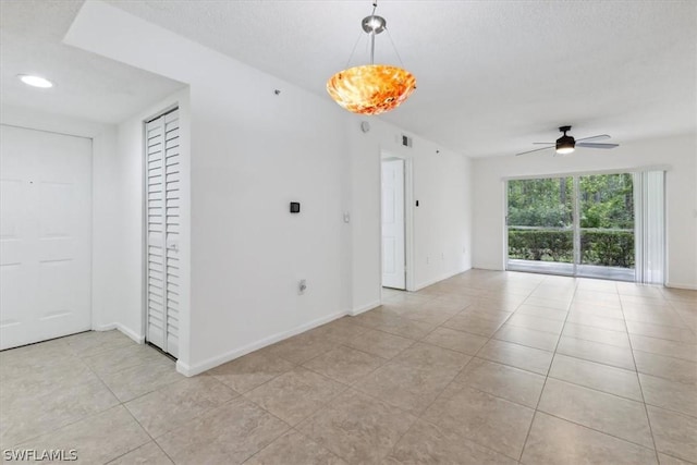 spare room featuring ceiling fan, a textured ceiling, and light tile patterned floors