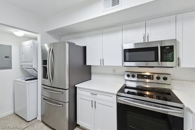 kitchen with white cabinetry, light tile patterned floors, stacked washing maching and dryer, electric panel, and appliances with stainless steel finishes