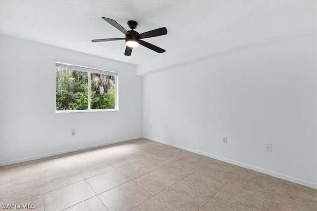 empty room with ceiling fan, light tile patterned floors, and a textured ceiling