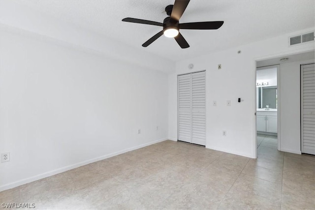 unfurnished bedroom featuring ceiling fan, connected bathroom, sink, and a closet