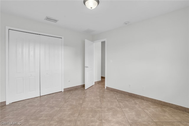 unfurnished bedroom featuring light tile patterned floors and a closet