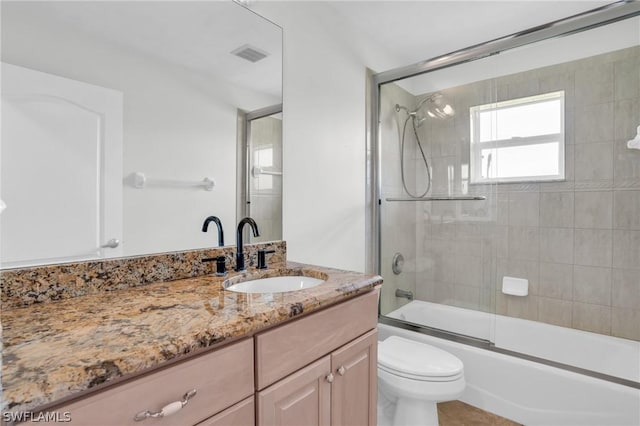 full bathroom featuring vanity, bath / shower combo with glass door, and toilet