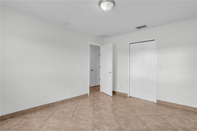 unfurnished bedroom featuring a closet and light tile patterned floors