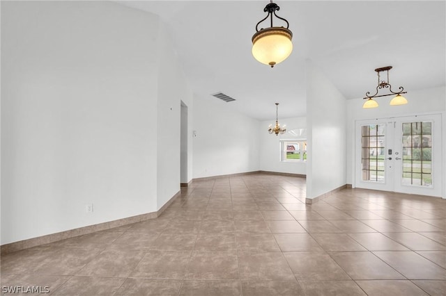 tiled empty room featuring vaulted ceiling, french doors, and a chandelier