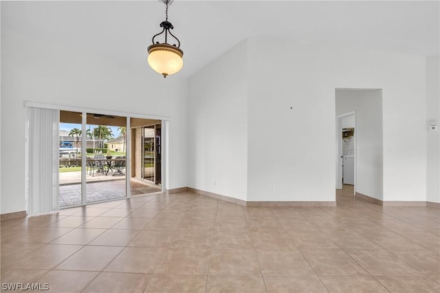 tiled spare room with washer / clothes dryer and a high ceiling