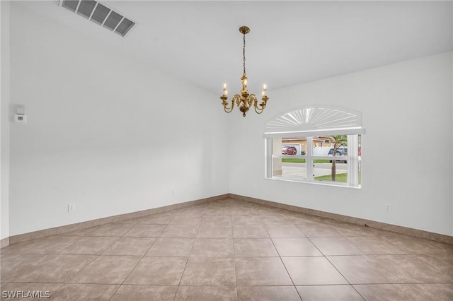 tiled spare room featuring an inviting chandelier