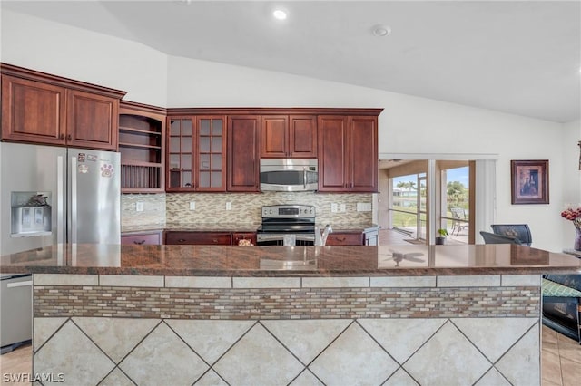 kitchen featuring light tile patterned floors, backsplash, vaulted ceiling, and appliances with stainless steel finishes