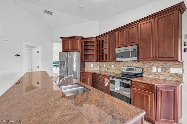 kitchen featuring vaulted ceiling, sink, backsplash, light stone counters, and stainless steel appliances