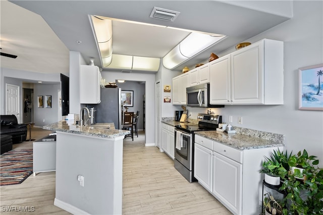 kitchen featuring light stone countertops, sink, light hardwood / wood-style flooring, white cabinets, and appliances with stainless steel finishes