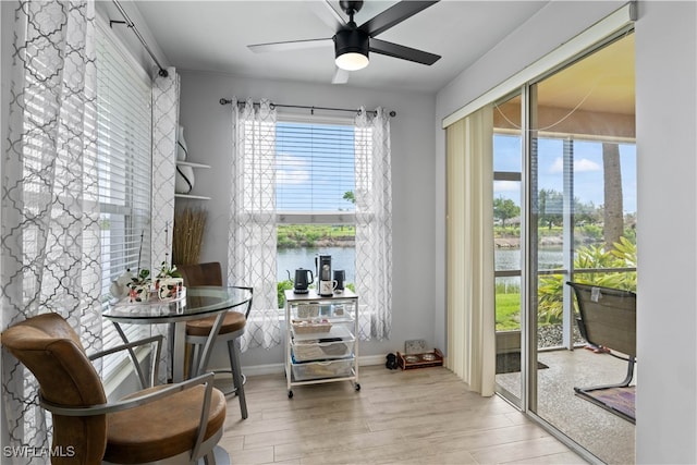 living area with a water view, light hardwood / wood-style flooring, and ceiling fan