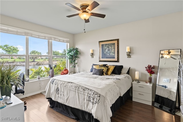 bedroom featuring dark hardwood / wood-style flooring, a water view, and ceiling fan