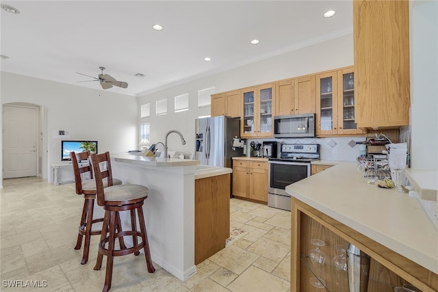 kitchen with appliances with stainless steel finishes, tasteful backsplash, ceiling fan, and ornamental molding