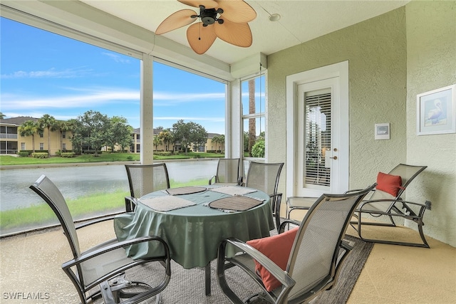 sunroom with ceiling fan and a water view