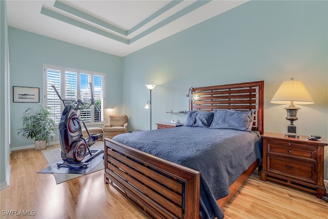 bedroom featuring a tray ceiling and light wood-type flooring