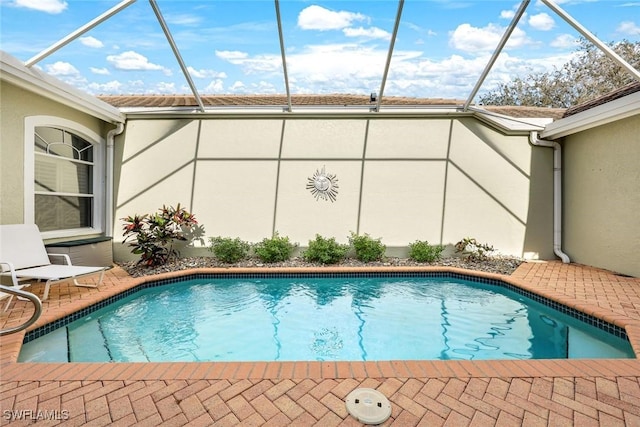 outdoor pool with glass enclosure and a patio