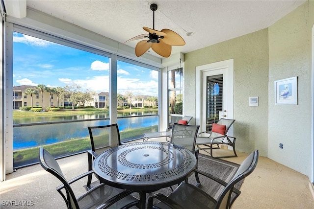 sunroom featuring a ceiling fan and a water view