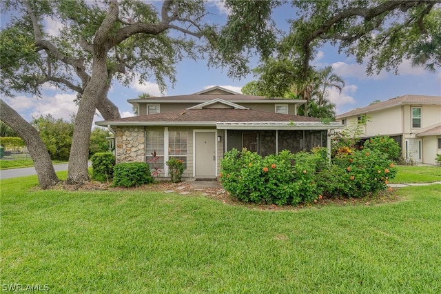 view of front of house featuring a sunroom and a front yard