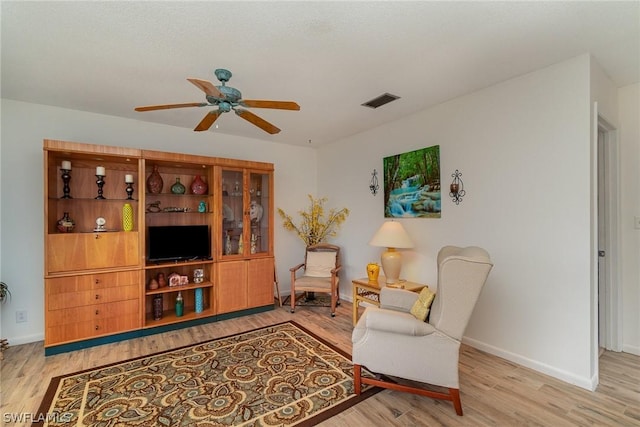 living area with light hardwood / wood-style flooring and ceiling fan