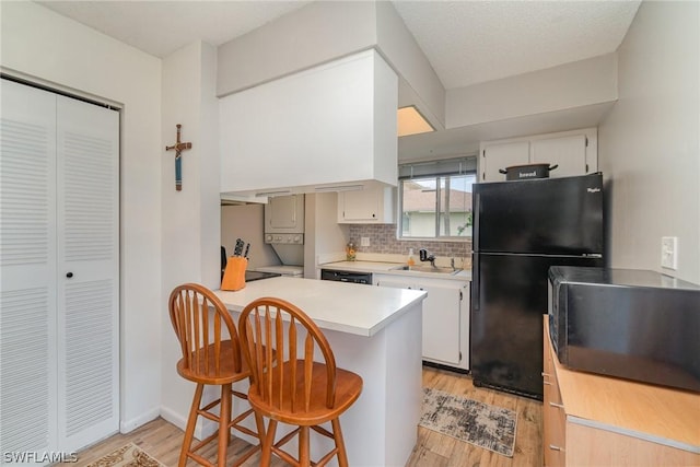 kitchen featuring white cabinetry, kitchen peninsula, sink, and black appliances