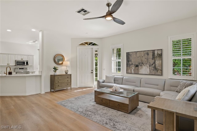 living room featuring light hardwood / wood-style floors, a healthy amount of sunlight, and ceiling fan