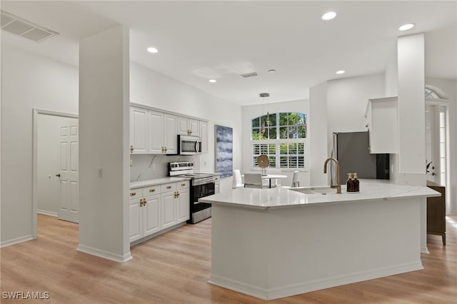 kitchen with stainless steel appliances, white cabinets, kitchen peninsula, backsplash, and light wood-type flooring