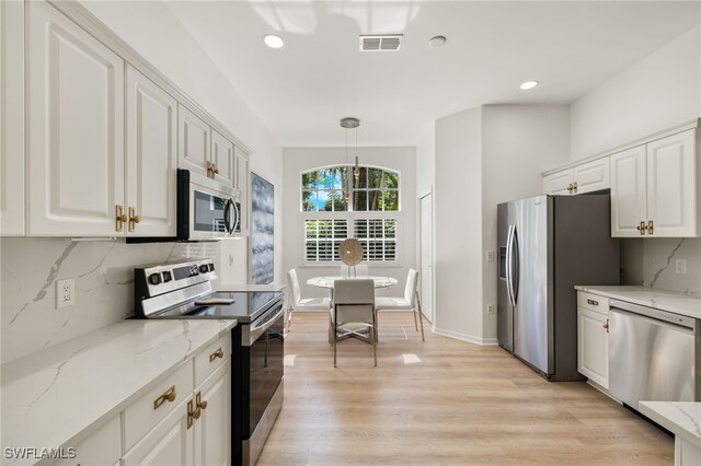 kitchen featuring tasteful backsplash, light wood-type flooring, white cabinets, light stone countertops, and appliances with stainless steel finishes