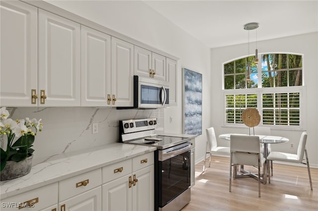 kitchen with white cabinetry, backsplash, hanging light fixtures, stainless steel appliances, and light wood-type flooring