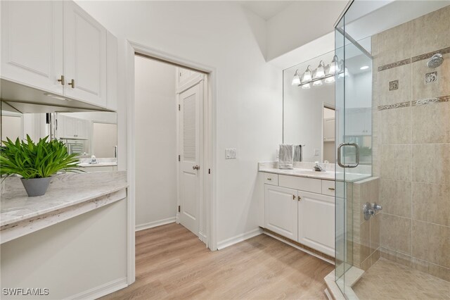 bathroom featuring vanity, a shower with door, and wood-type flooring