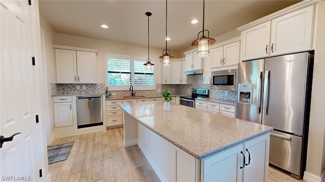 kitchen with decorative backsplash, a center island, light hardwood / wood-style flooring, and appliances with stainless steel finishes