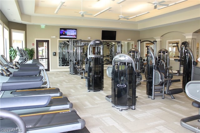 workout area featuring ornate columns, ceiling fan, a raised ceiling, and light colored carpet