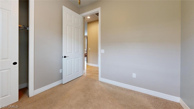 unfurnished bedroom with light carpet and a closet