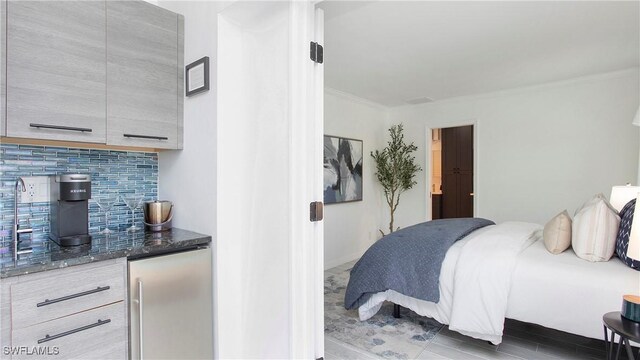 bedroom featuring stainless steel fridge and ornamental molding