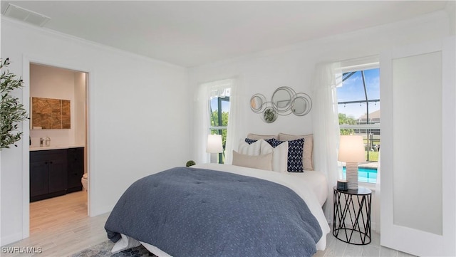 bedroom with ensuite bathroom, ornamental molding, and light hardwood / wood-style flooring