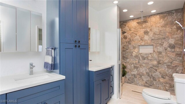 bathroom featuring tiled shower, vanity, and toilet