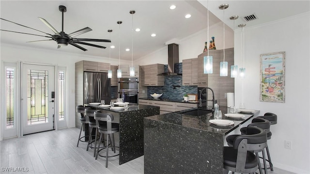 kitchen with wall chimney range hood, a breakfast bar area, stainless steel refrigerator, double oven, and hanging light fixtures