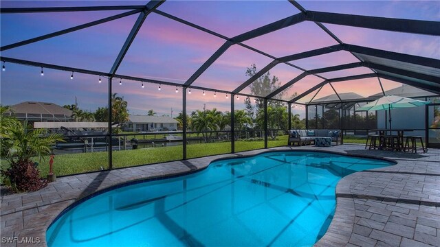 pool at dusk with a patio, an outdoor hangout area, and glass enclosure