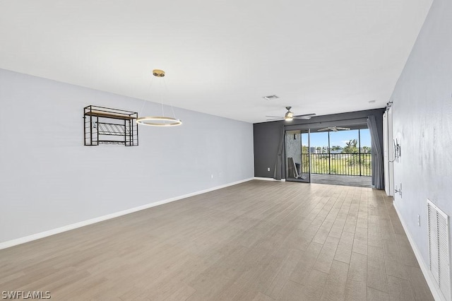 empty room featuring a ceiling fan, baseboards, visible vents, and wood finished floors